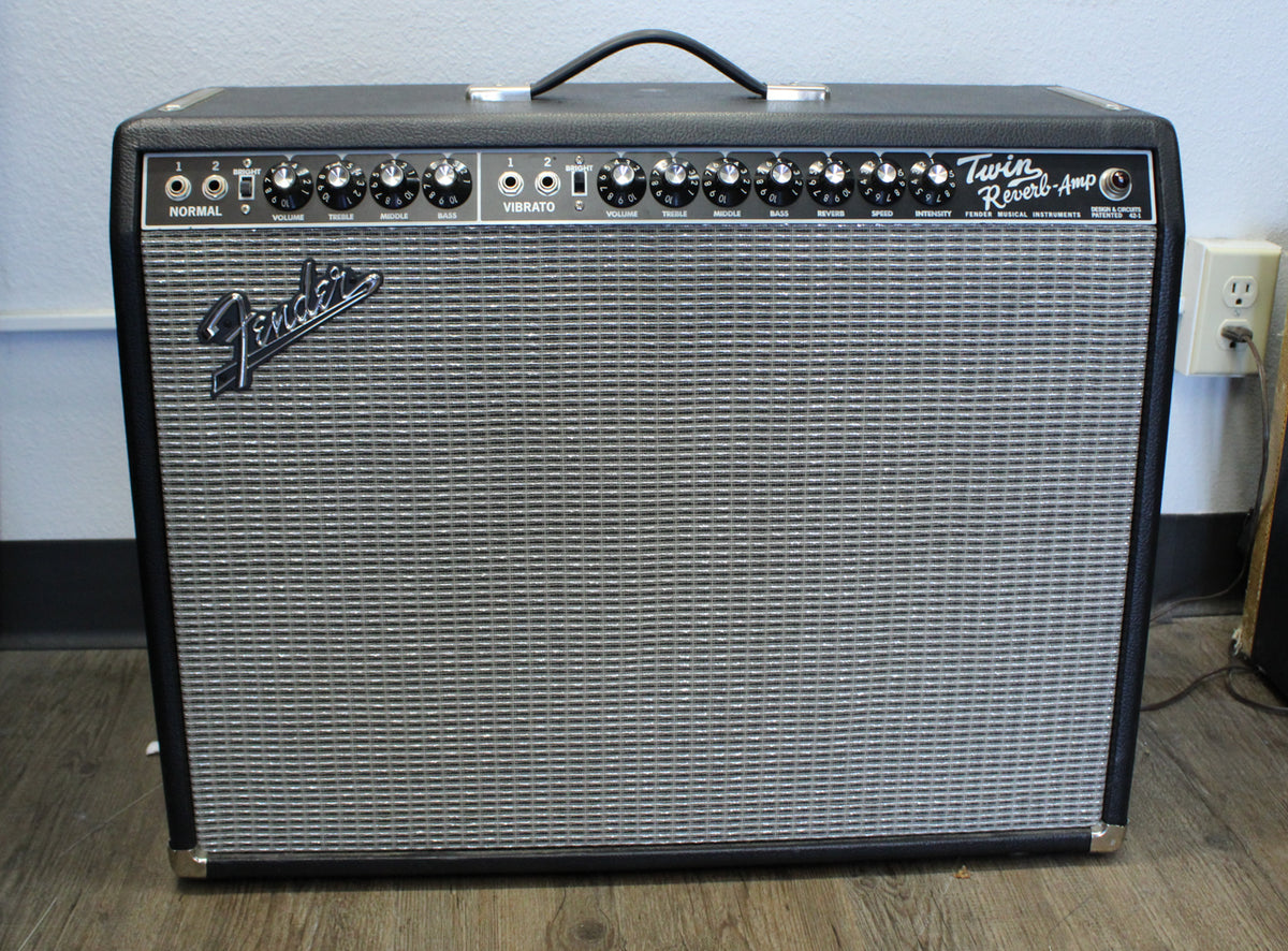 Full front view of a black combo amp with a silver grille, black control panel, and a black handle on top.