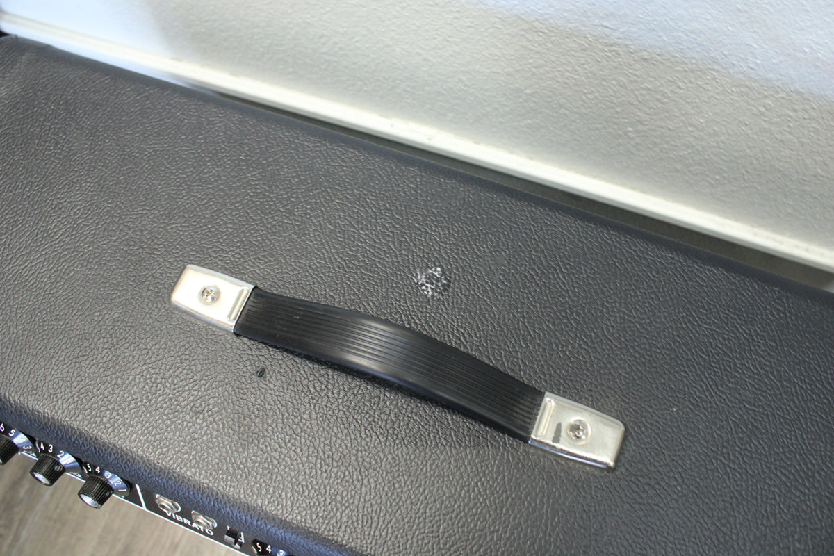 Overhead view of the black textured amp top, showing the black plastic handle with chrome end caps and a small scuff mark.