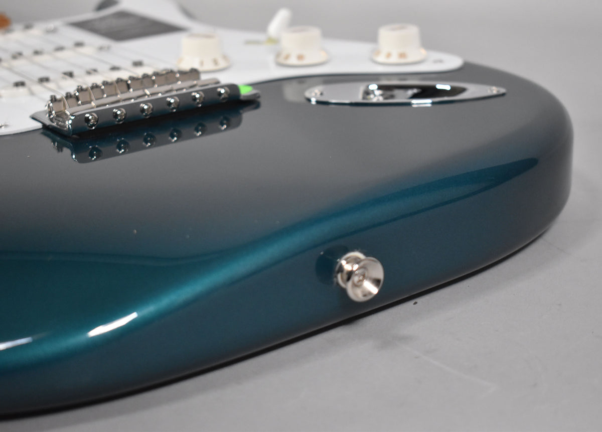 A close-up of the guitar's lower body, showing the metallic Ocean Turquoise finish, chrome bridge, output jack, and cream control knobs.