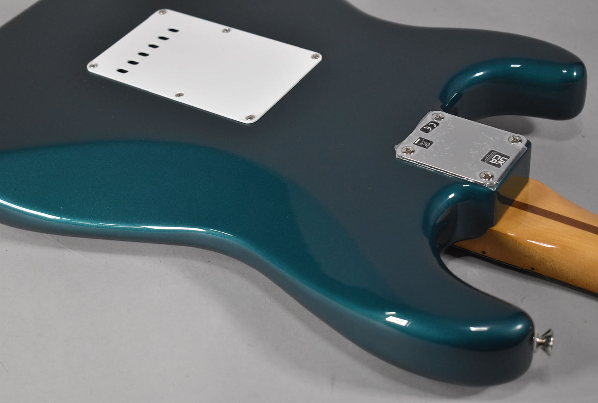 The back of an Ocean Turquoise Stratocaster, showing the white tremolo cover, chrome neck plate, and a light wood neck.