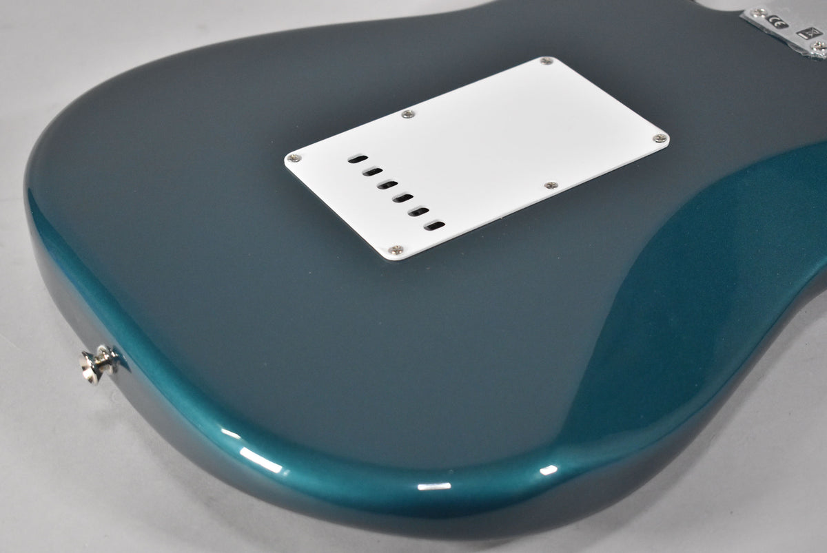 The back of an Ocean Turquoise Stratocaster, showing the white tremolo cover and a chrome strap button on the lower bout.