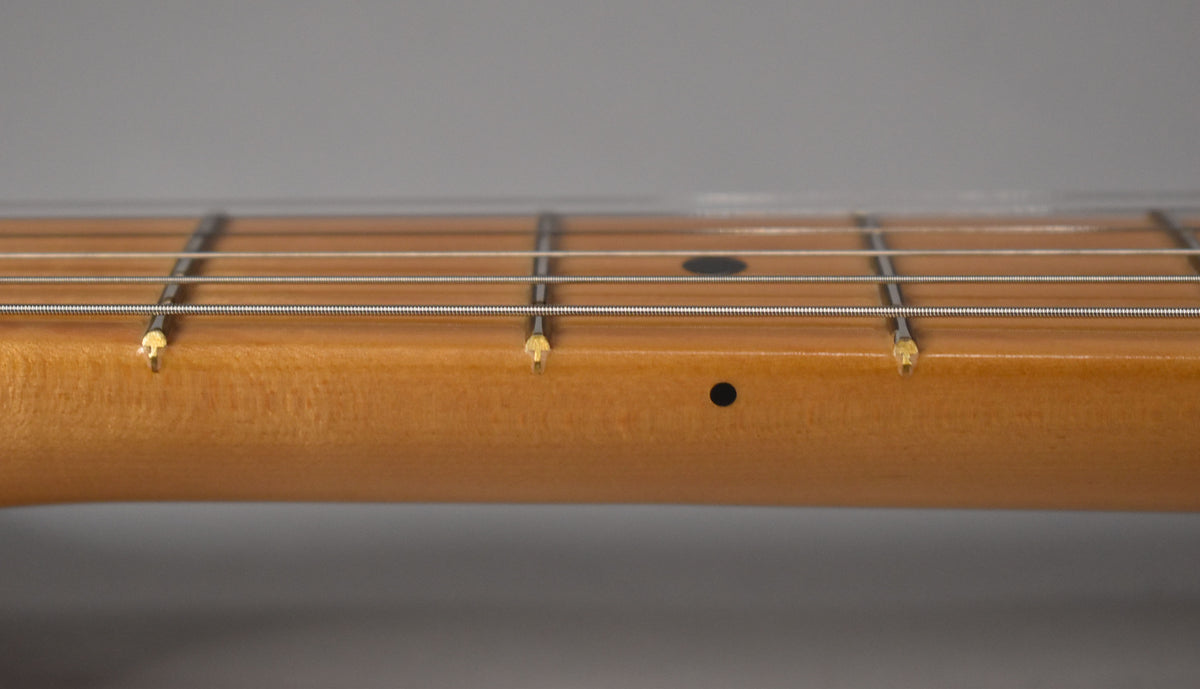 Close-up of the light brown maple neck and fretboard, showing black dot inlays at the 7th and 9th frets.