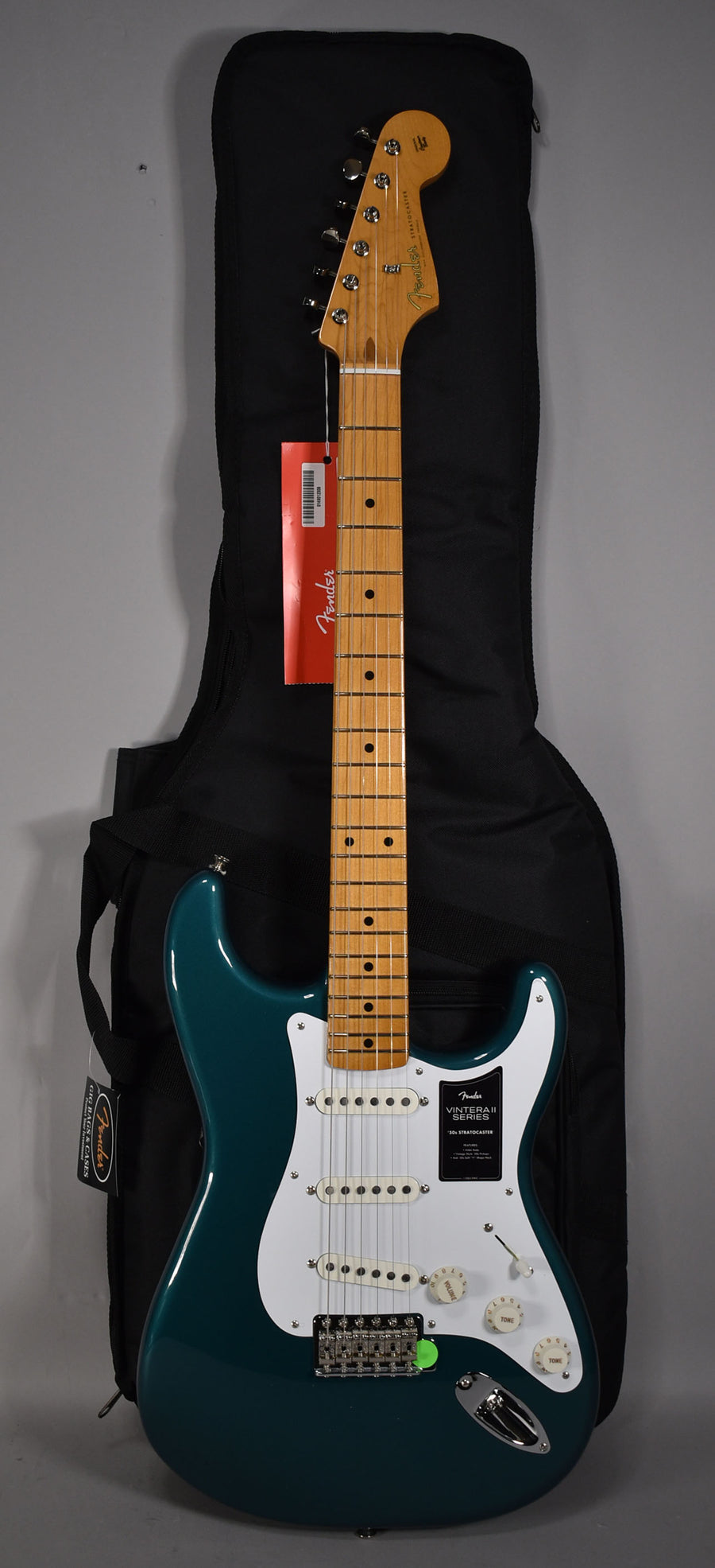 Full-length view of a glossy ocean turquoise Stratocaster with a maple neck, white pickguard, three single-coil pickups, and chrome hardware.