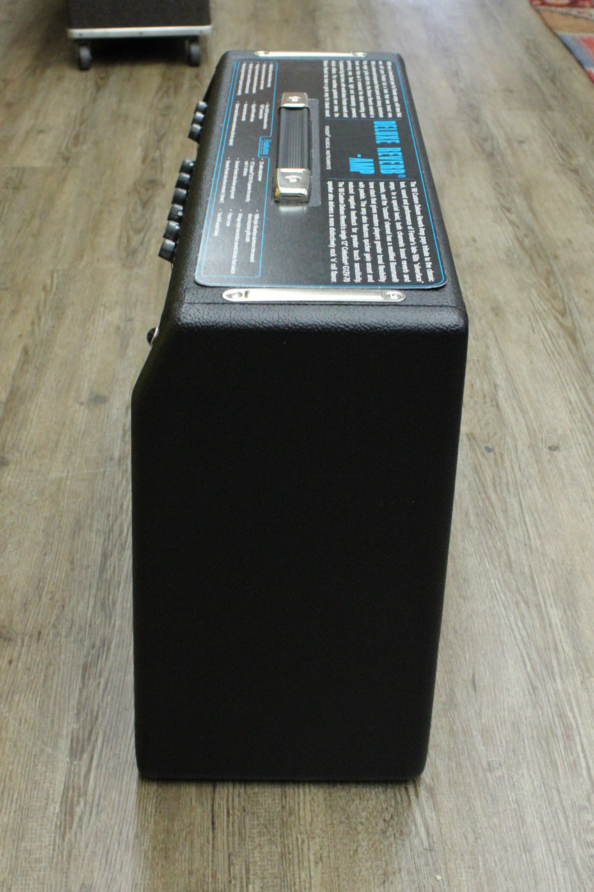 Top-down view of the black textured combo amp, showing the chrome-capped handle and a row of black control knobs.
