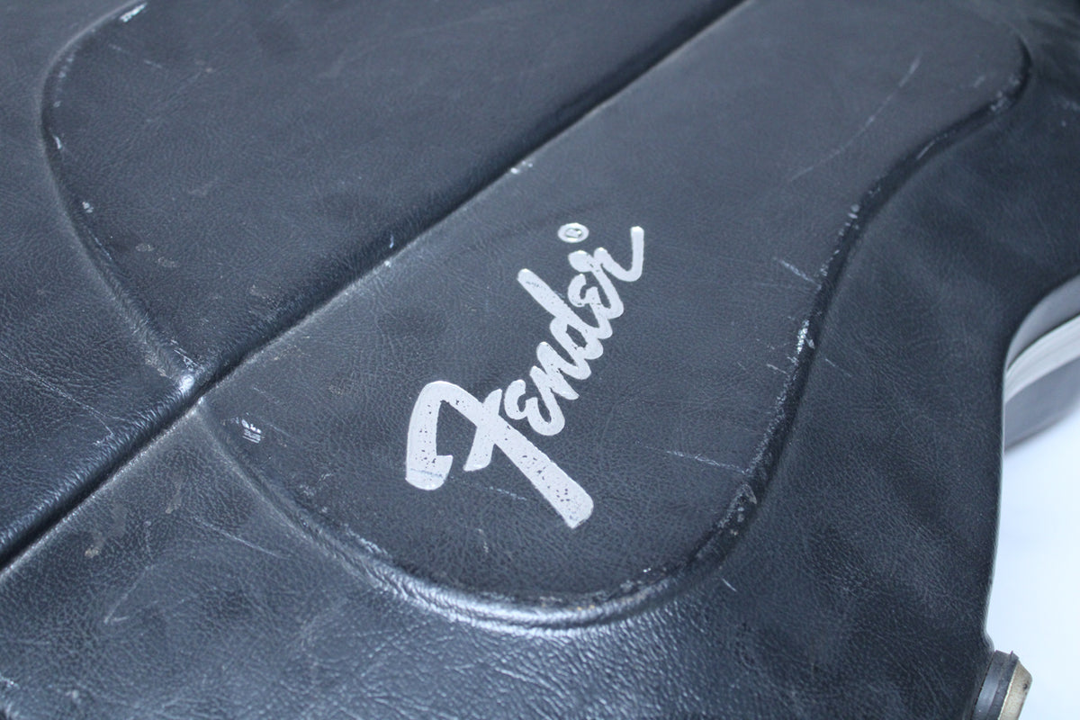 Close-up of the black textured case, showing the silver "Fender" logo and several scuffs and scratches on the surface.