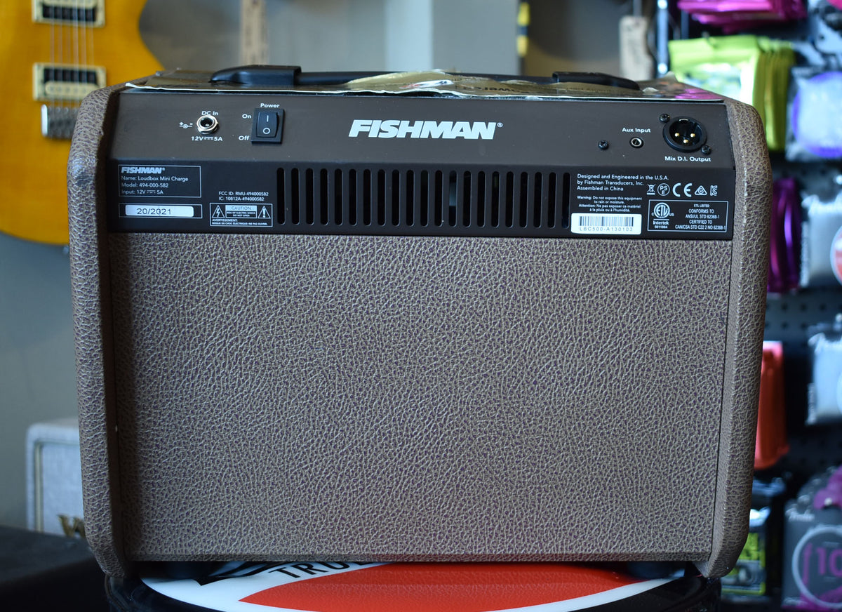 The brown textured amplifier is seen from the rear, showing the power switch, DC input, Aux input, and Mix D.I. Output.