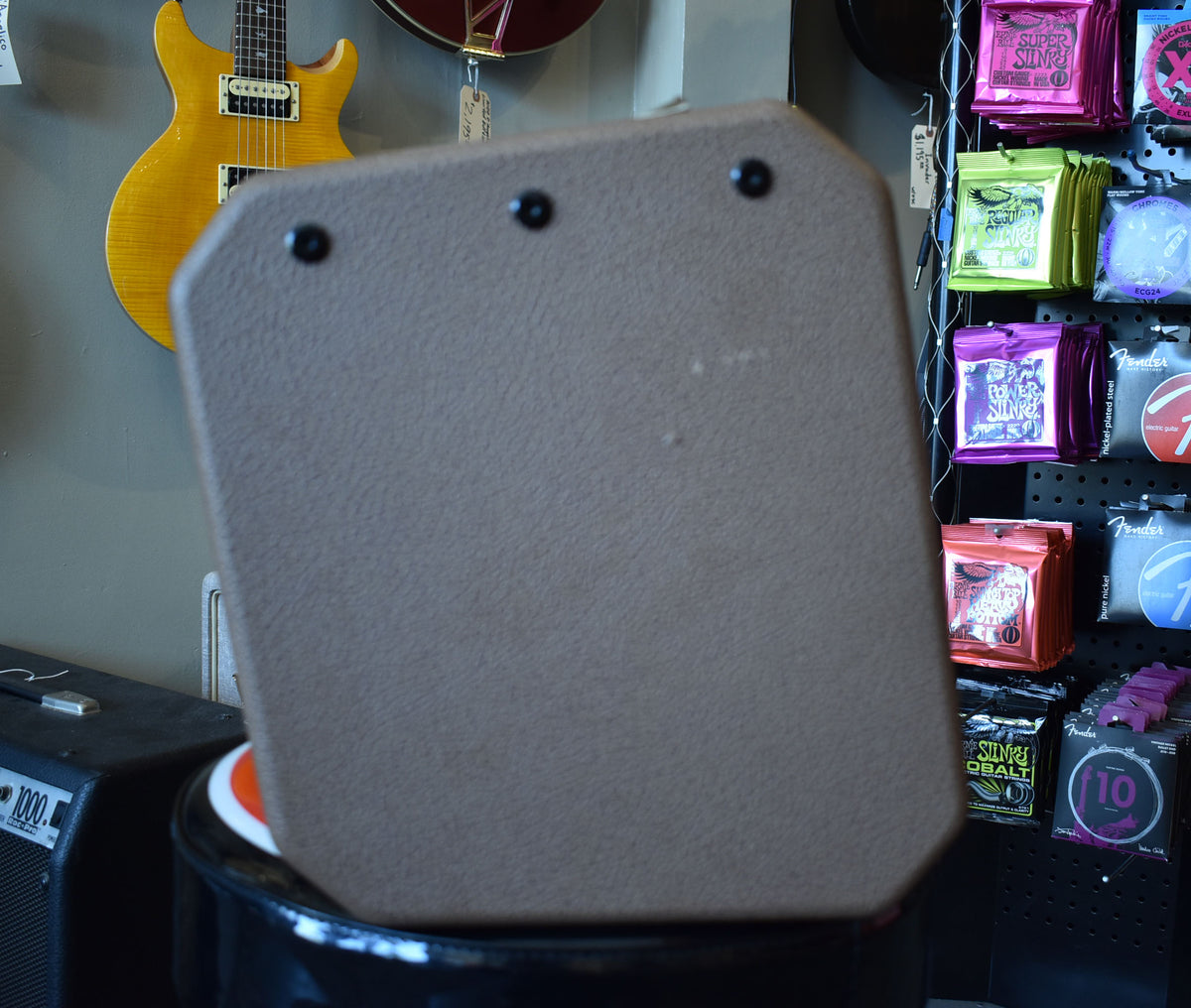 The brown textured amplifier is angled, showing its flat, octagonal back panel with three visible black screws along the top edge.