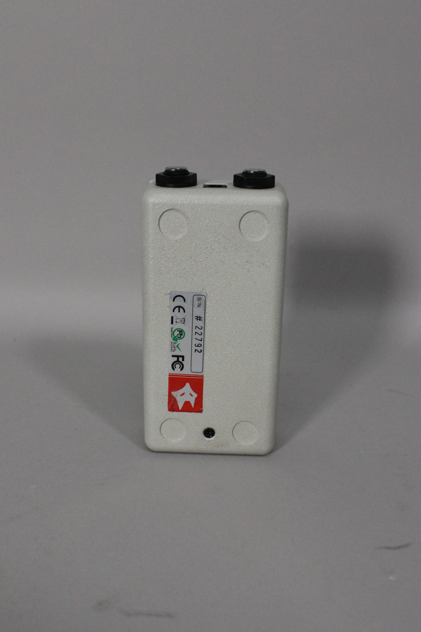 The off-white interface is viewed from the top-rear, showing two black knobs and a sticker with a serial number.