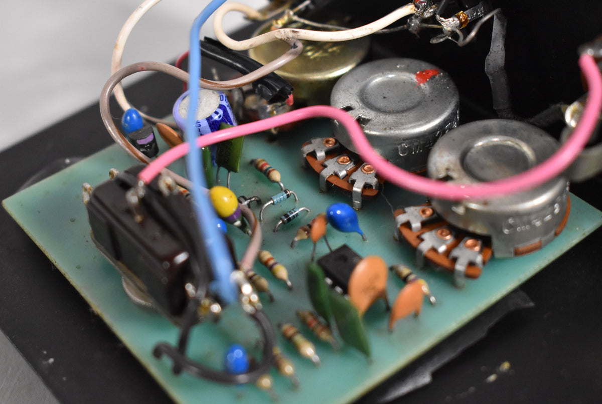Close-up of the pedal's internal circuit board, showing various colorful components, wires, and two silver potentiometers with red markings.