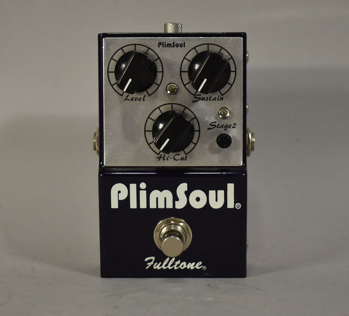 Dark blue pedal with a brushed metal top panel, three large black control knobs, a smaller black button, and a silver footswitch.