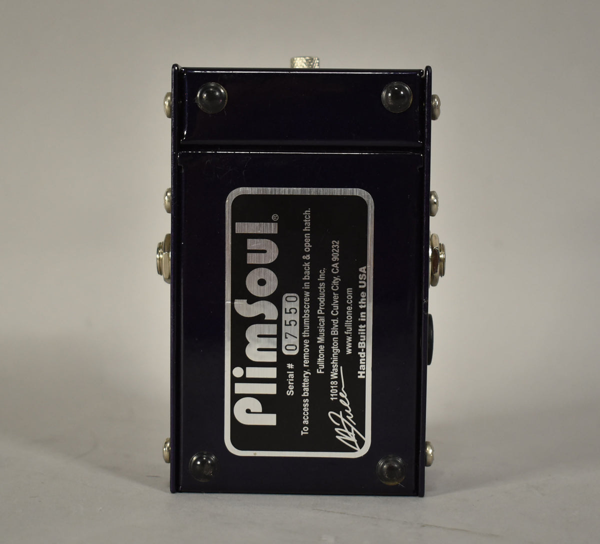 The dark blue pedal is viewed from the back, showing a large white serial number sticker and silver screws.