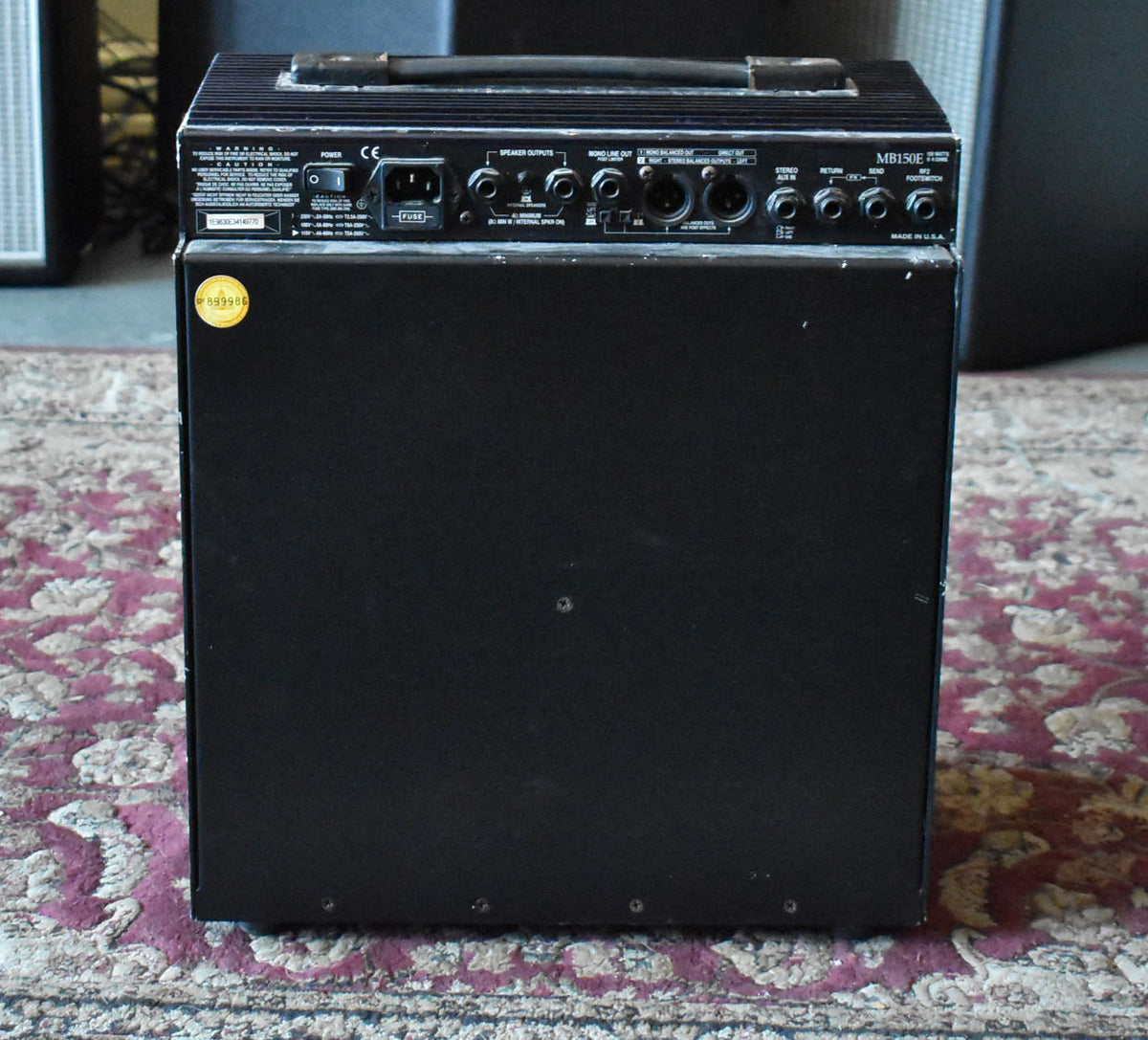 Rear view of the black combo amp, showing the top control panel with various inputs/outputs and a carry handle.