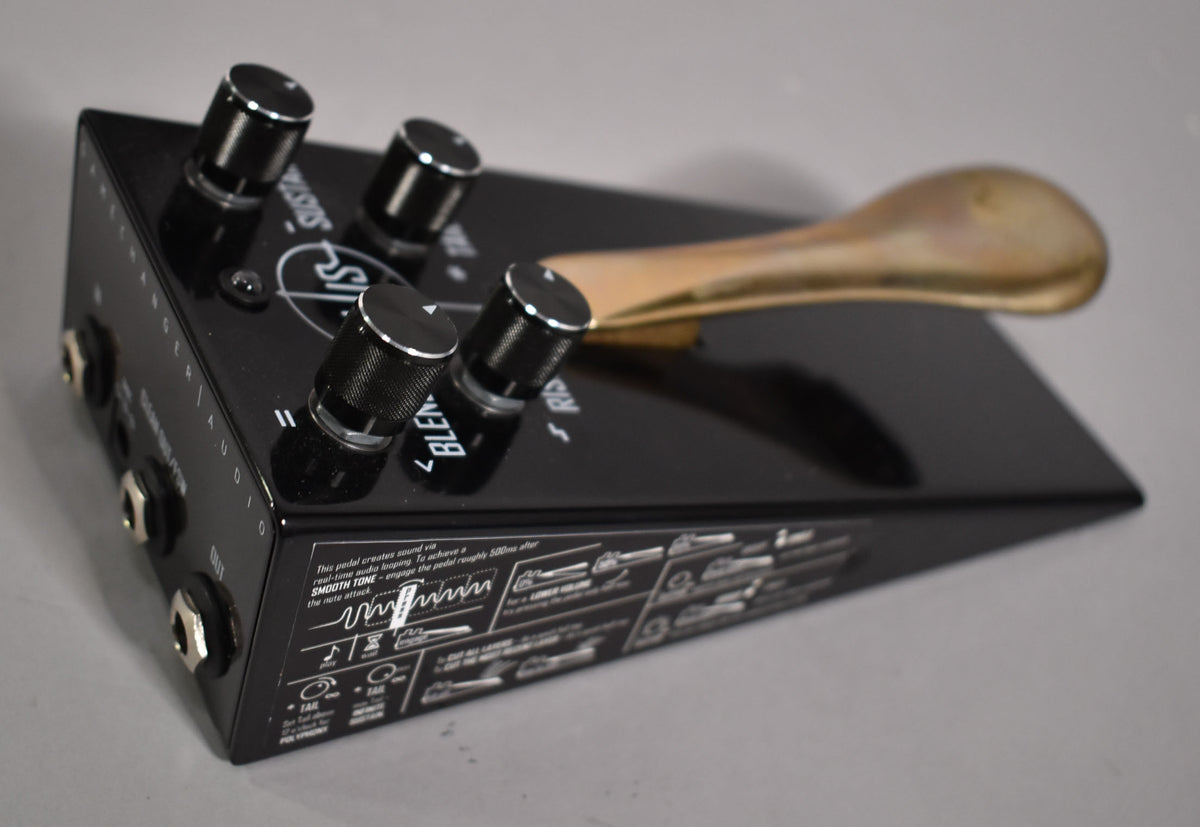 The black pedal is angled from the left, showing four black knurled control knobs with silver tops and a gold-colored sustain pedal.
