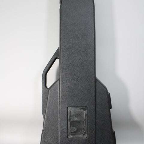 Black textured plastic guitar case, viewed from the front, showing a molded handle and a rectangular recessed area.