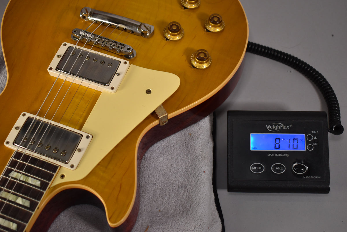 Upper body of a lemon burst guitar with cream binding, pickguard, and pickup rings, next to a scale displaying "8'10".