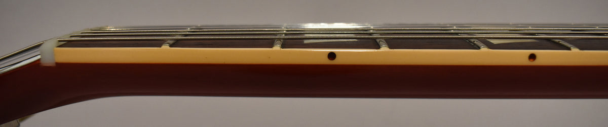 Close-up of the guitar's dark brown neck and fretboard, showing the cream binding, frets, and trapezoid inlays.