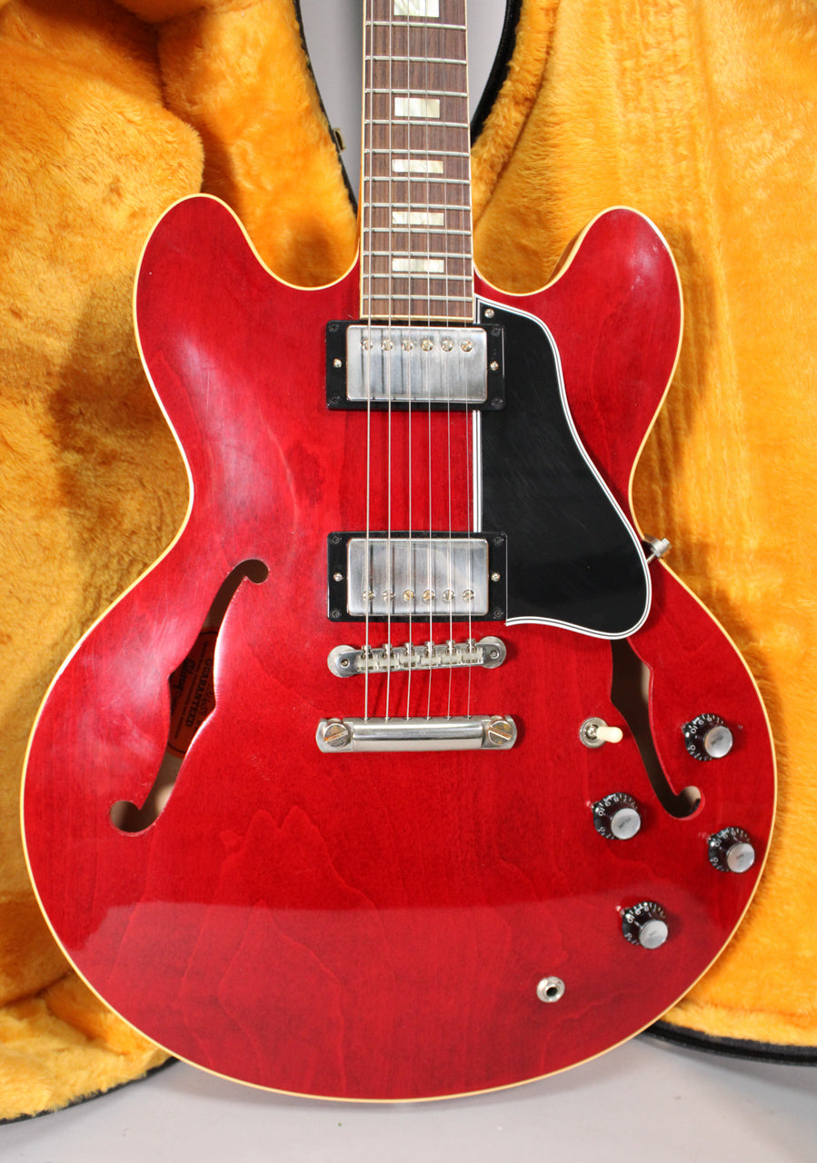 Cherry red semi-hollowbody electric guitar, angled to show the body, neck, and headstock, with a black pickguard and chrome hardware.
