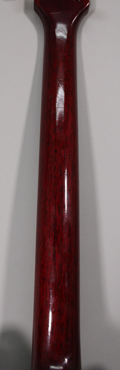 The back of the cherry-finished guitar neck, showing extensive finish checking and wear, with a lighter, worn patch near the heel.