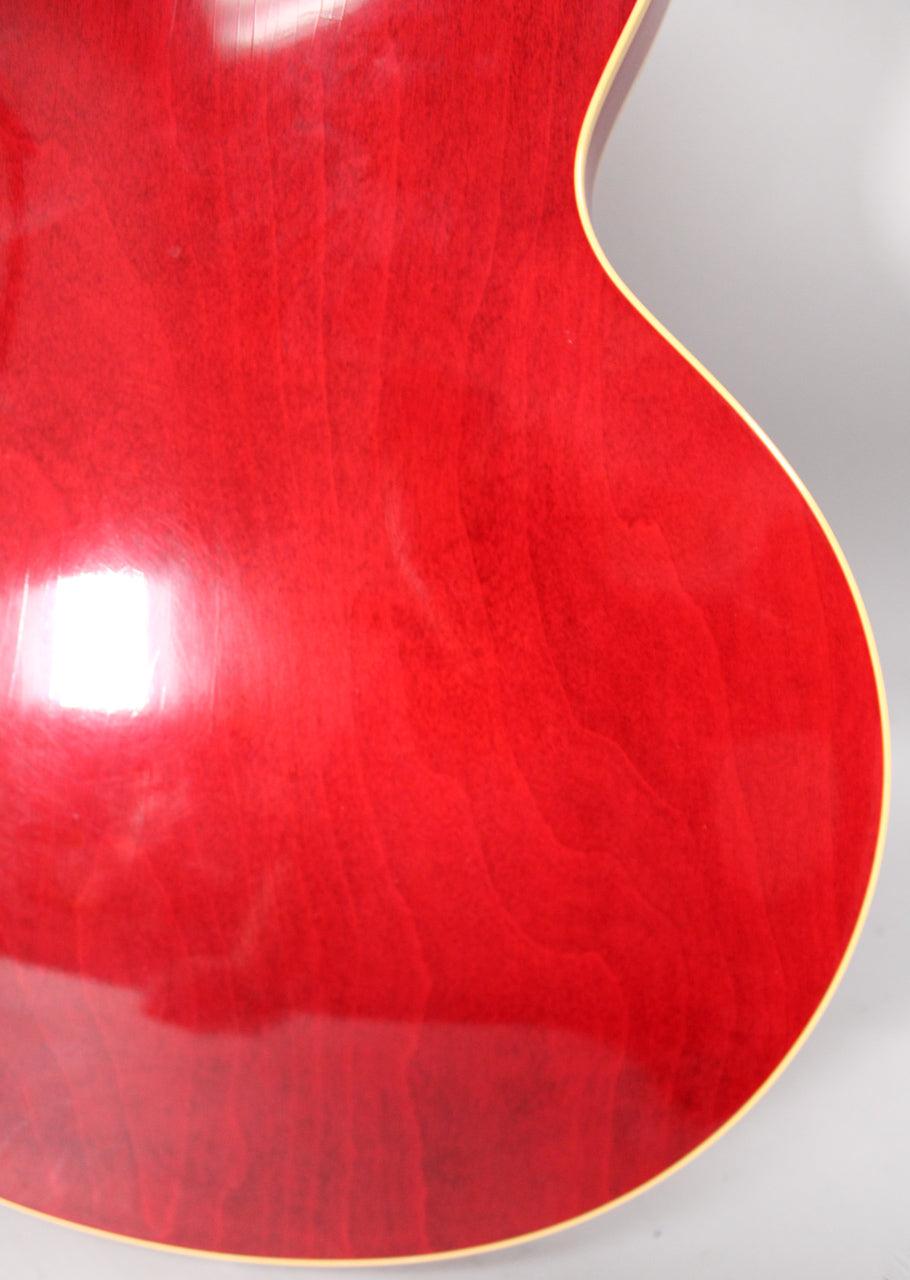 Close-up of the guitar's lower bout, showing the cherry finish with visible wood grain and light aging, framed by cream binding.