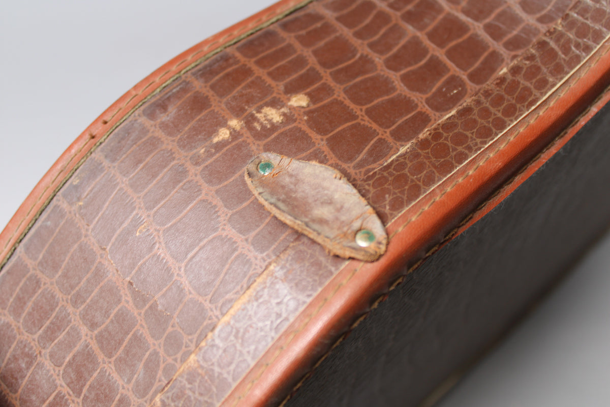 Close-up of the brown snakeskin-textured case, showing a worn leather strap with two green rivets and some scuffing.