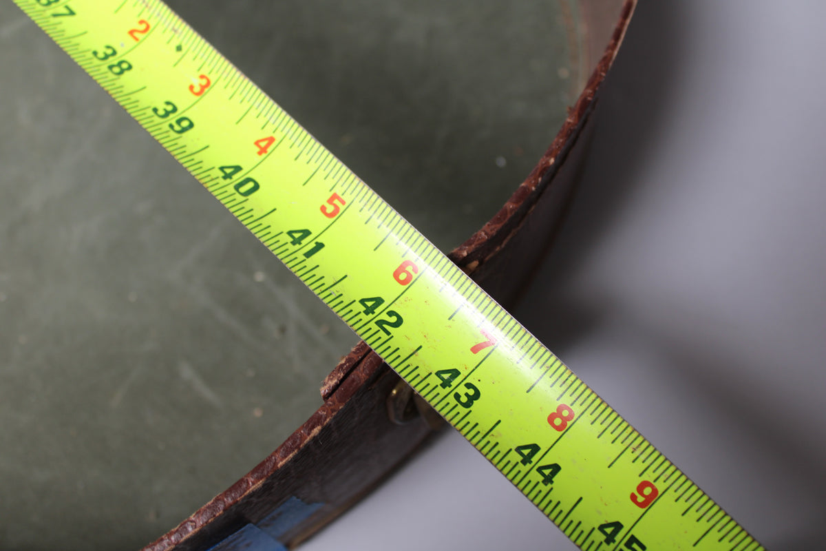 A yellow tape measure shows the case's width at 42 inches, revealing a dark green interior and worn brown leather trim.