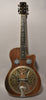 A full-front view of a warm brown resonator guitar with a distressed brass resonator cone and two round sound screens.