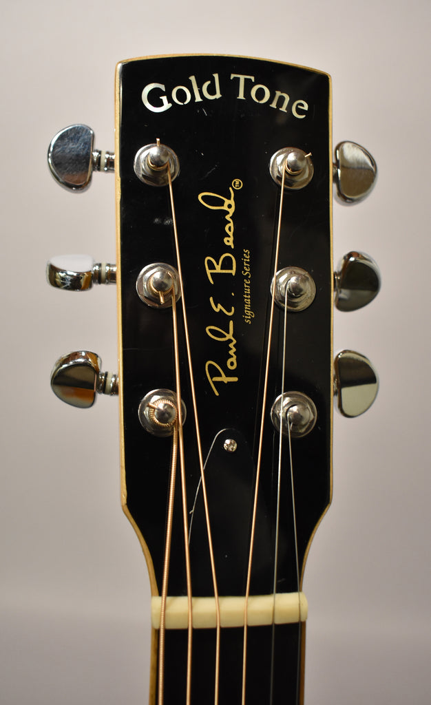 Close-up of the black gloss headstock with six chrome tuners, showing light scratches and a cream binding.