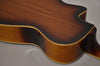 The resonator guitar's lower bout and cutaway are visible, showing a dark brown sunburst finish with light binding and a glossy neck heel.