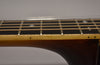 Close-up of the guitar's dark brown neck and light brown fretboard, showing copper strings, silver frets, and diamond inlays.
