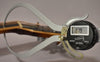 A digital caliper measures the string height at the nut of the guitar, displaying "0.79" on its screen.