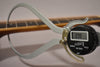 A digital caliper measures the neck relief at the 7th fret, displaying 0.98mm, with the fretboard in soft focus.