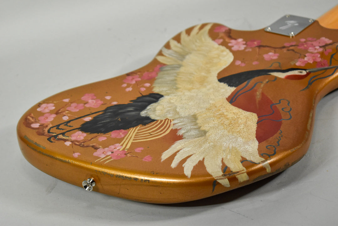 Close-up of the guitar's lower body, showing a hand-painted crane with outstretched wings and cherry blossoms on a gold finish.