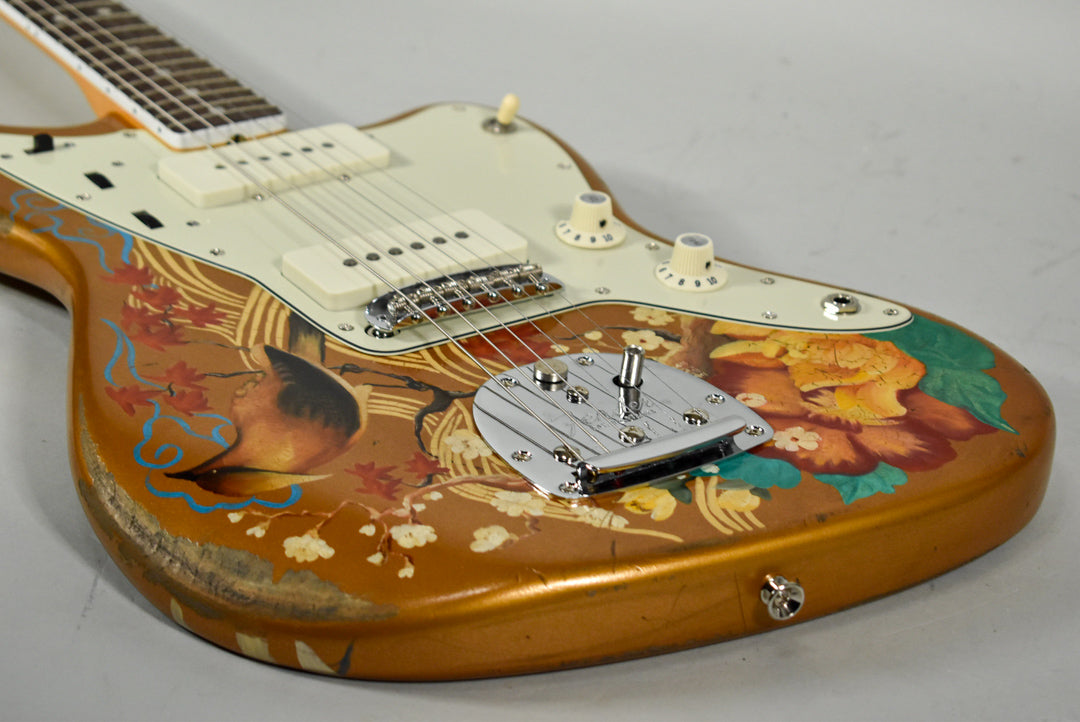 Close-up of the guitar body, showing the gold finish with a hand-painted bird and floral design, cream pickguard, and chrome hardware.