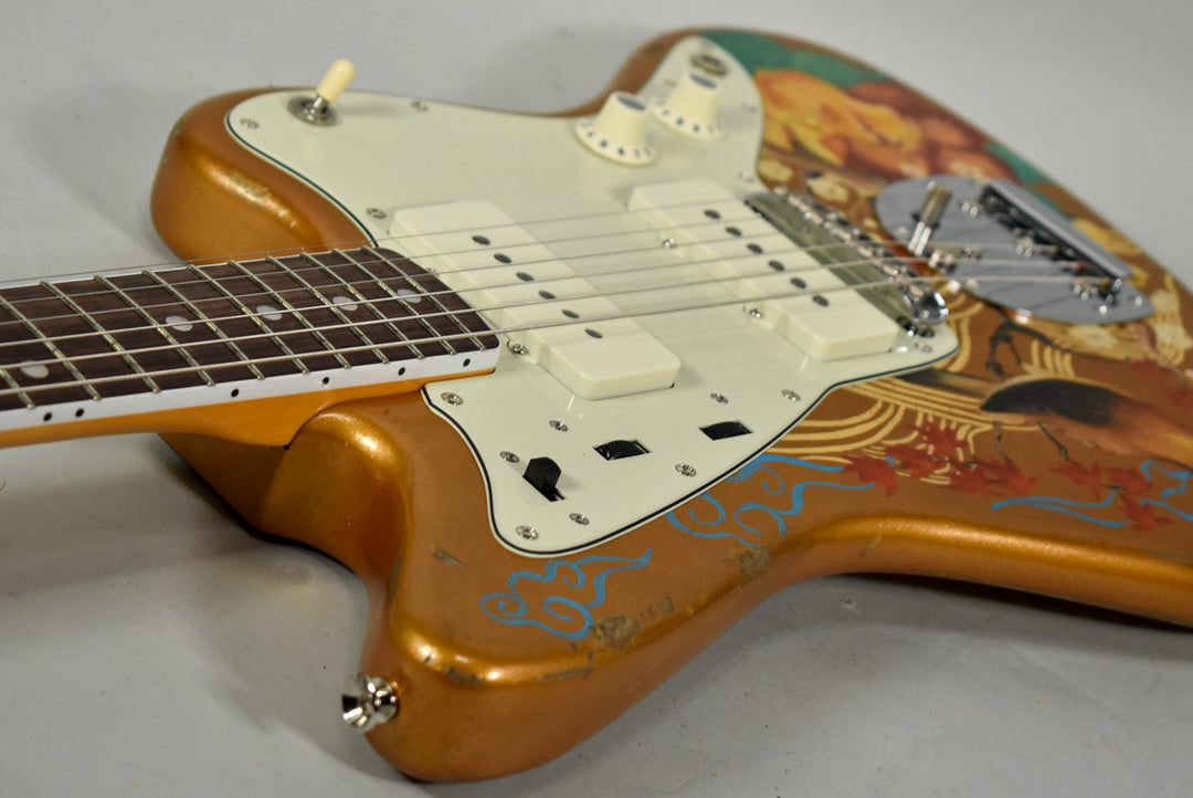 Close-up of the Jazzmaster's body, showing the gold finish with hand-painted Asian art, cream pickguard, and white pickups.