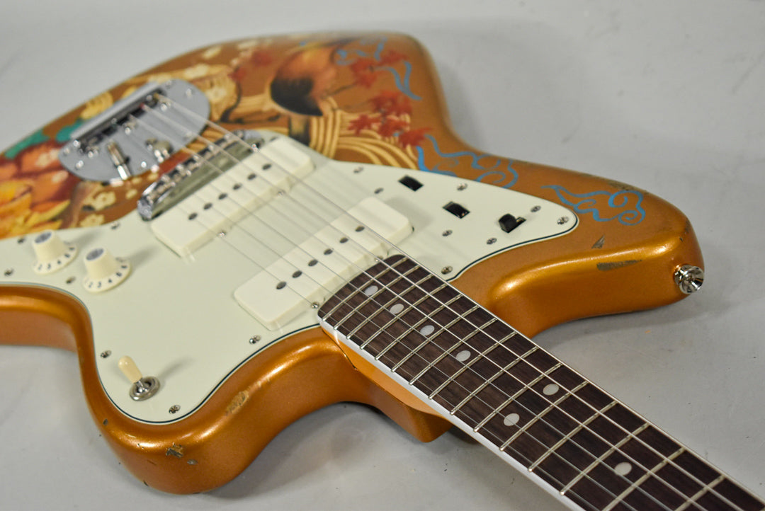 The gold Jazzmaster body, with an ornate hand-painted design, shows visible wear and chipping around the edges of its white pickguard.
