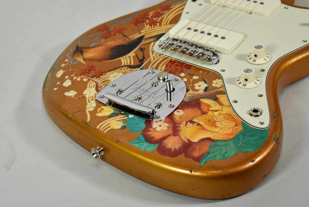 Close-up of the guitar's lower body, showing a bird and floral art on a gold finish with visible wear and a chrome tremolo.