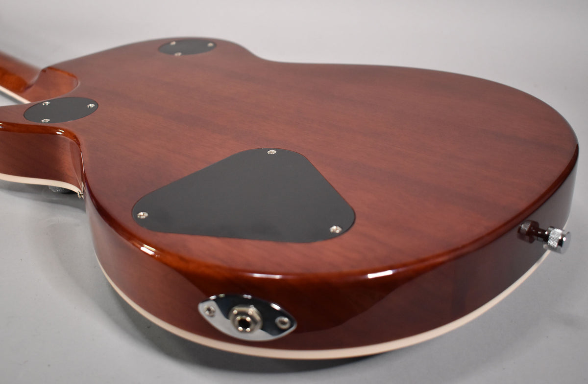 The guitar's glossy reddish-brown back is angled, showing three black control cavity covers, a chrome output jack, and a strap button.