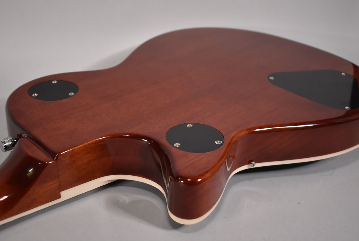 The guitar's mahogany back and sides are visible, with three black control cavity covers and cream binding along the body's edge.