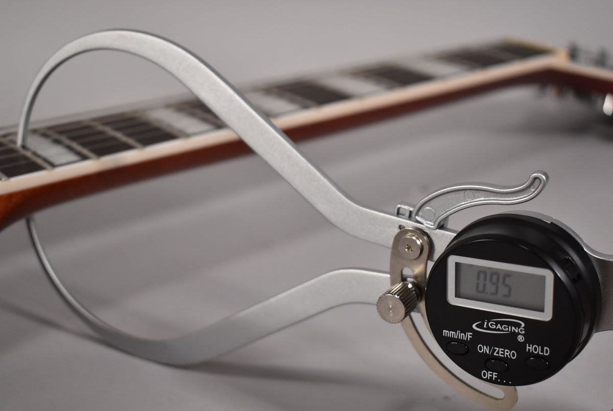 A digital caliper measures the guitar's neck thickness at 0.95 inches, with the fretboard and frets visible in the background.