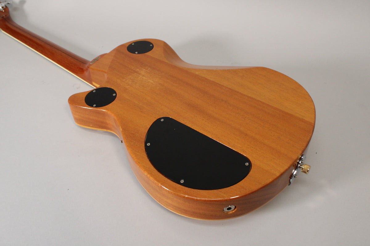 The back of an antique maple guitar, showing the neck joint, two round black control covers, and a larger black control cover.