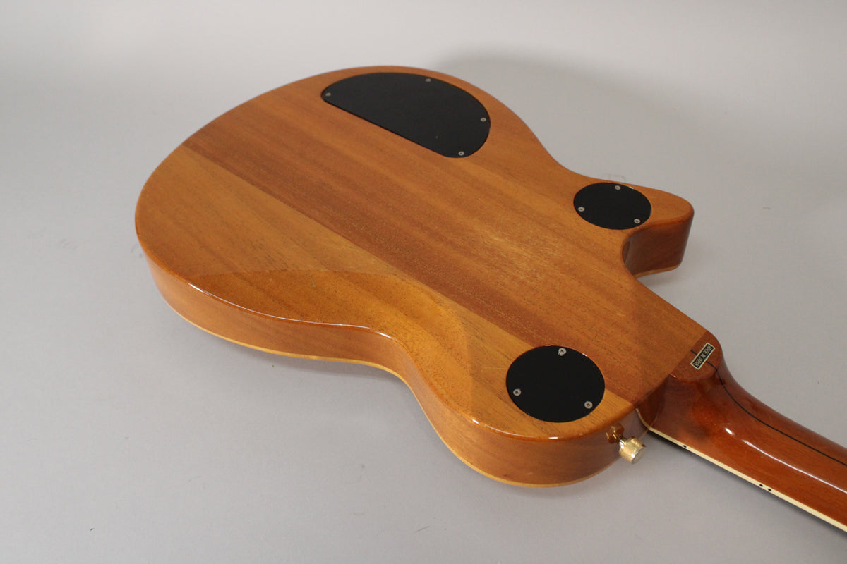 The back of the antique maple guitar body is shown, revealing three black control plates and a gold strap button.