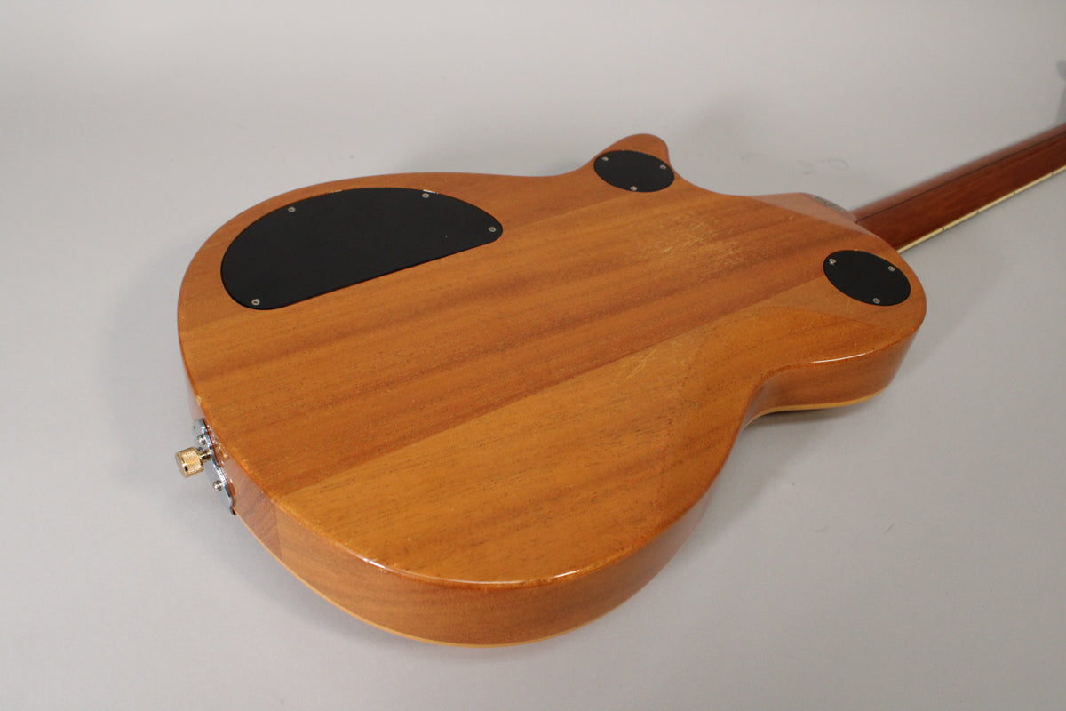The guitar's antique maple back, with a glossy finish, shows light wear and three black control cavity covers.