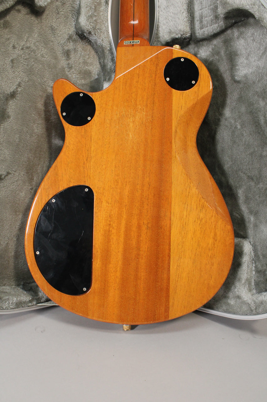 The back of the antique maple guitar body is visible, showing three black control cavity covers and a gold strap button.