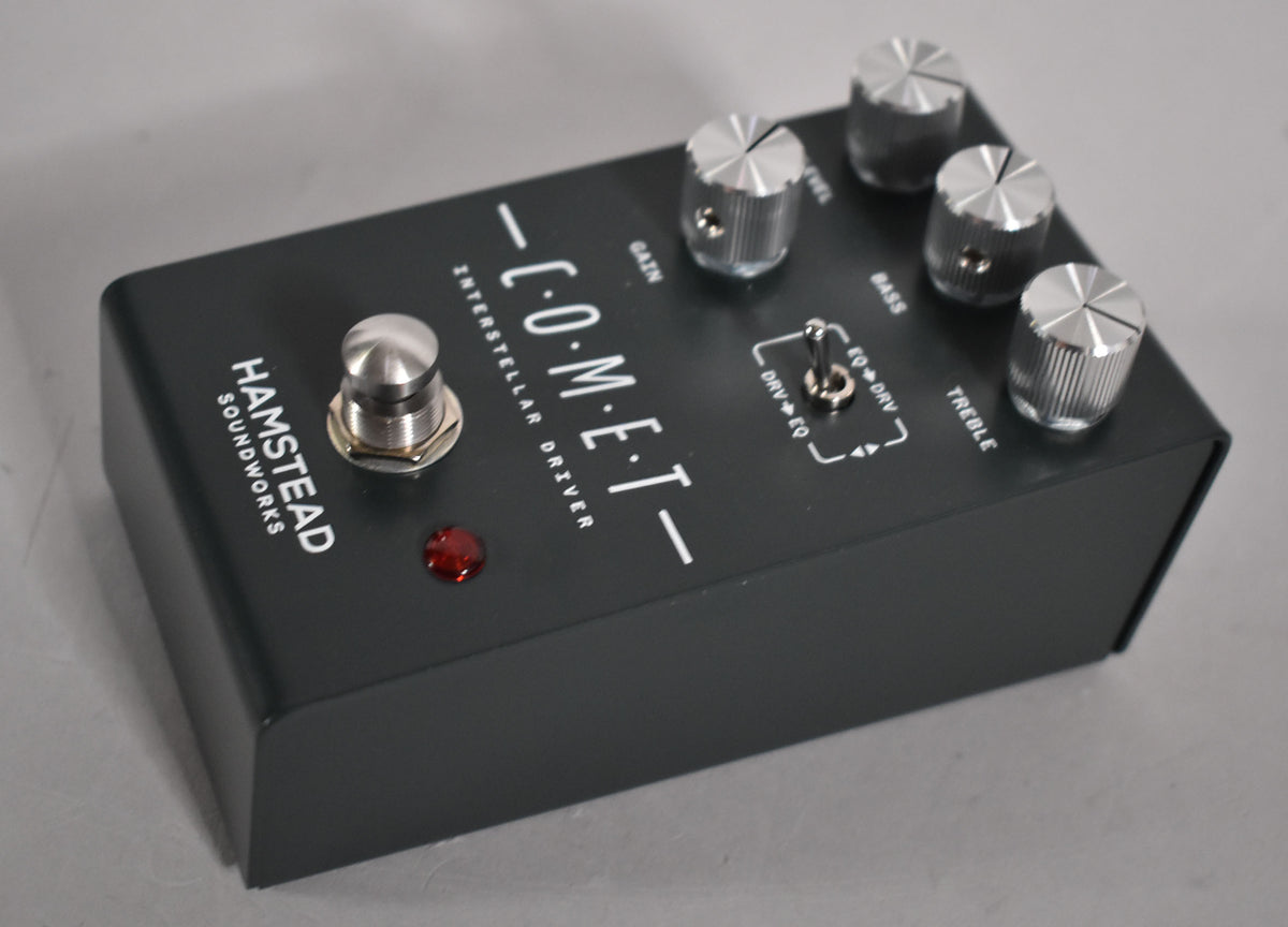A dark gray overdrive pedal, angled from the front right, with four silver knurled control knobs and a silver footswitch.
