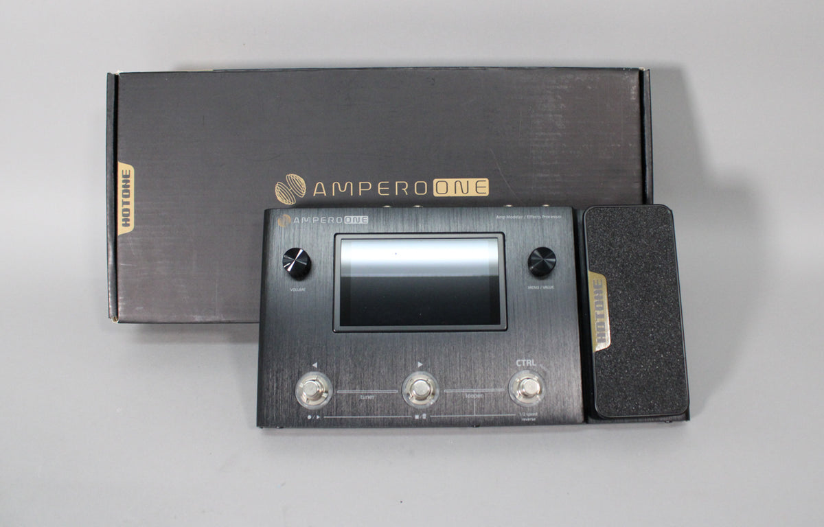 A dark grey multi-effects pedal with a large screen, three footswitches, two control knobs, and an expression pedal.