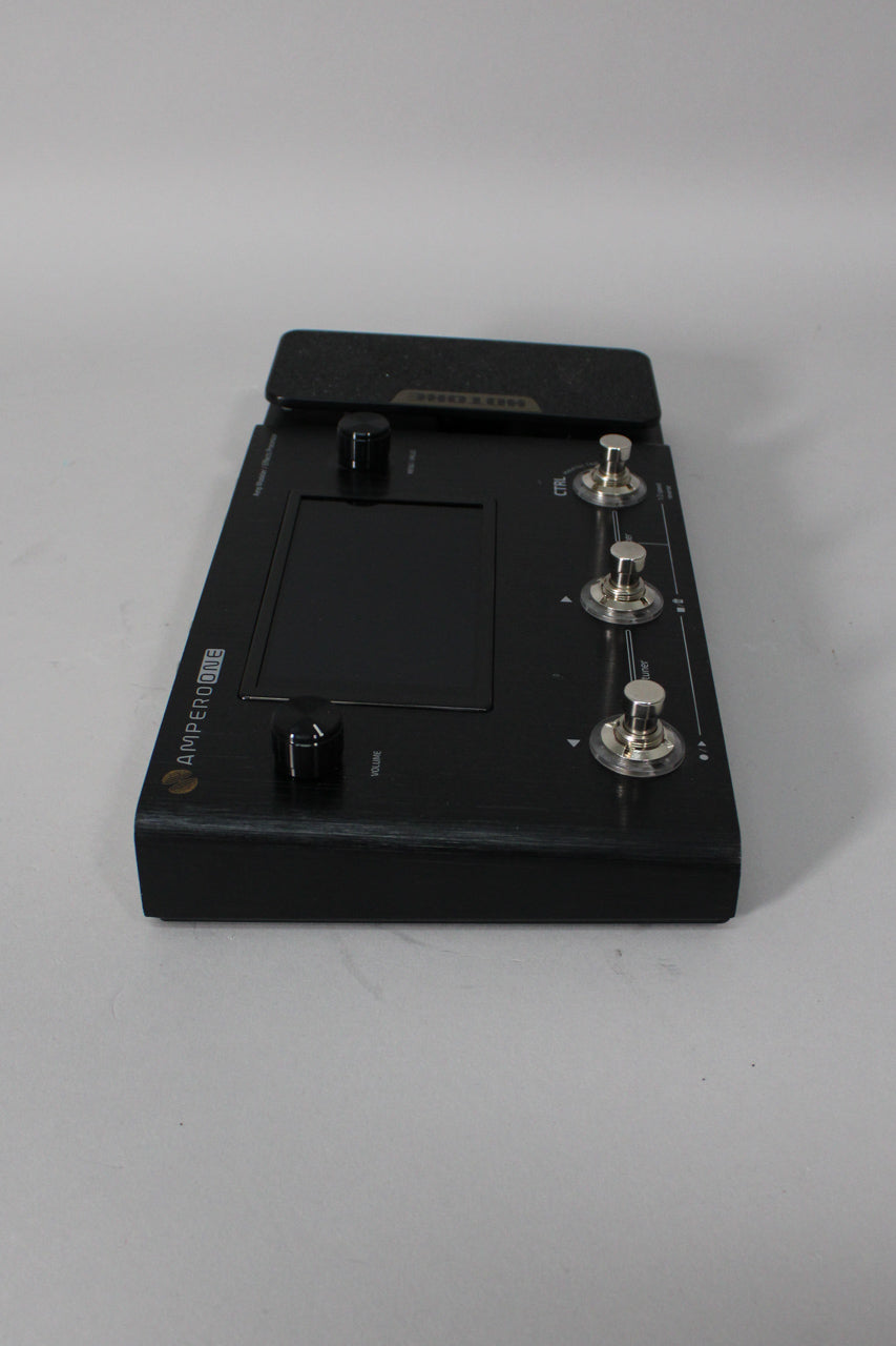 Angled view of a black brushed metal multi-effects pedal with a screen, three footswitches, two knobs, and an expression pedal.