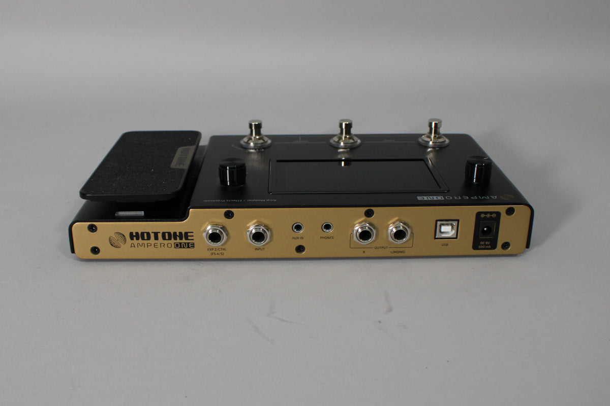 A black and gold multi-effects pedal, angled to show the rear panel with multiple jacks, a USB port, and power input.