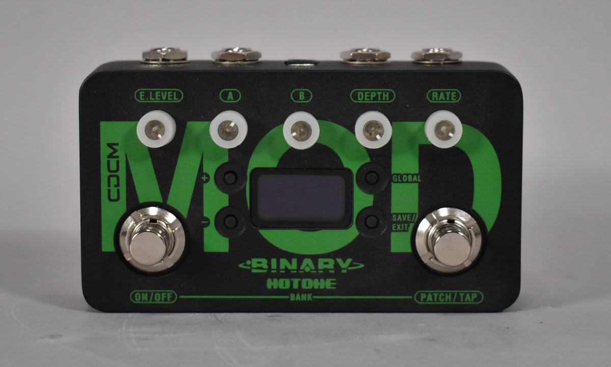 A black pedal with green "MOD" lettering, five white-ringed knobs, two footswitches, and a small rectangular screen.