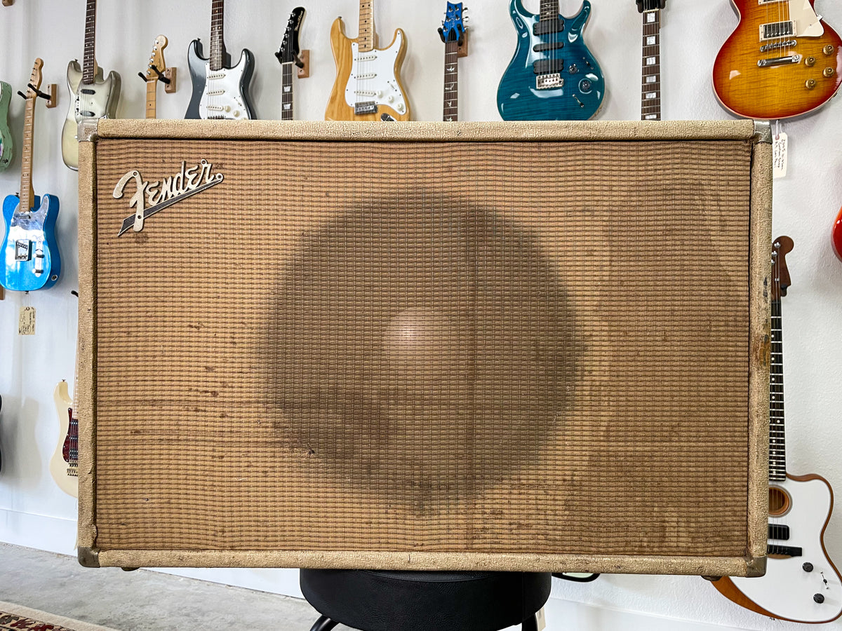 Front view of a large, rectangular blonde speaker cabinet with a dark brown grille cloth, showing wear and discoloration.