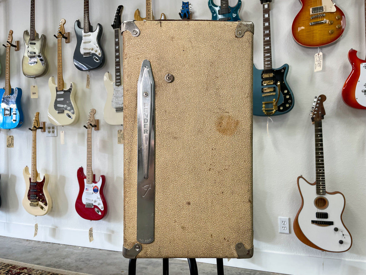 Full-height view of a blonde speaker cabinet with a vertical chrome strip handle and visible wear and discoloration.